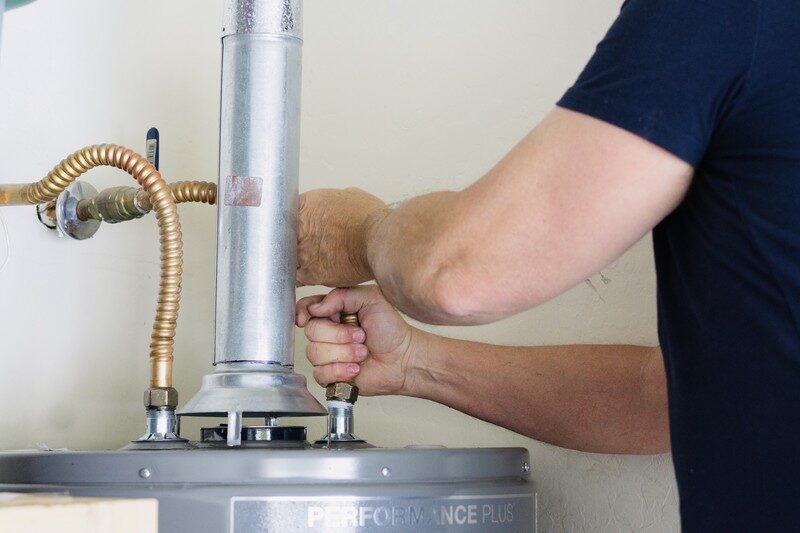 Plumber tightening connections on a residential tank water heater